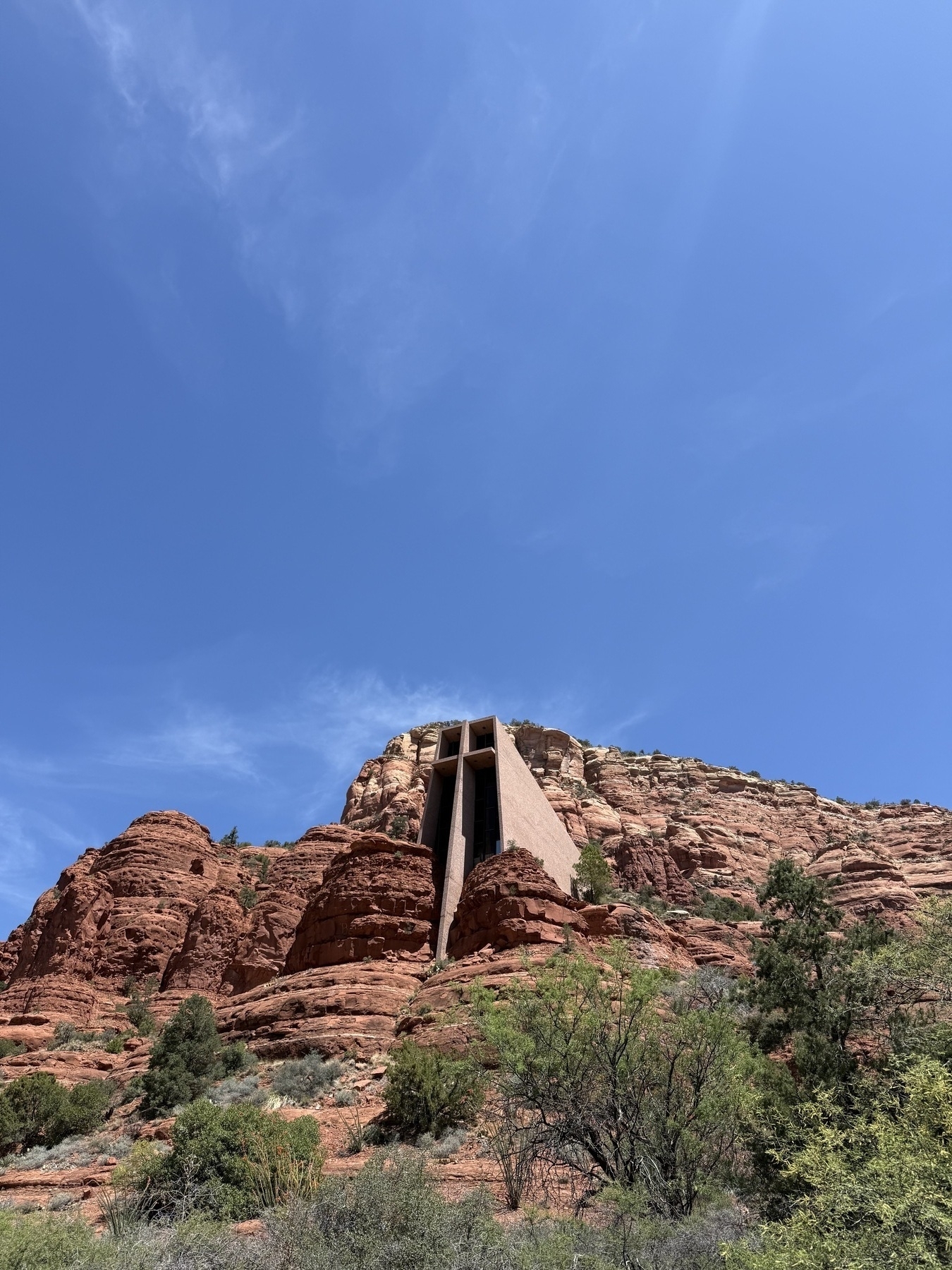 A modern chapel is nestled within the red rock formations under a clear blue sky.